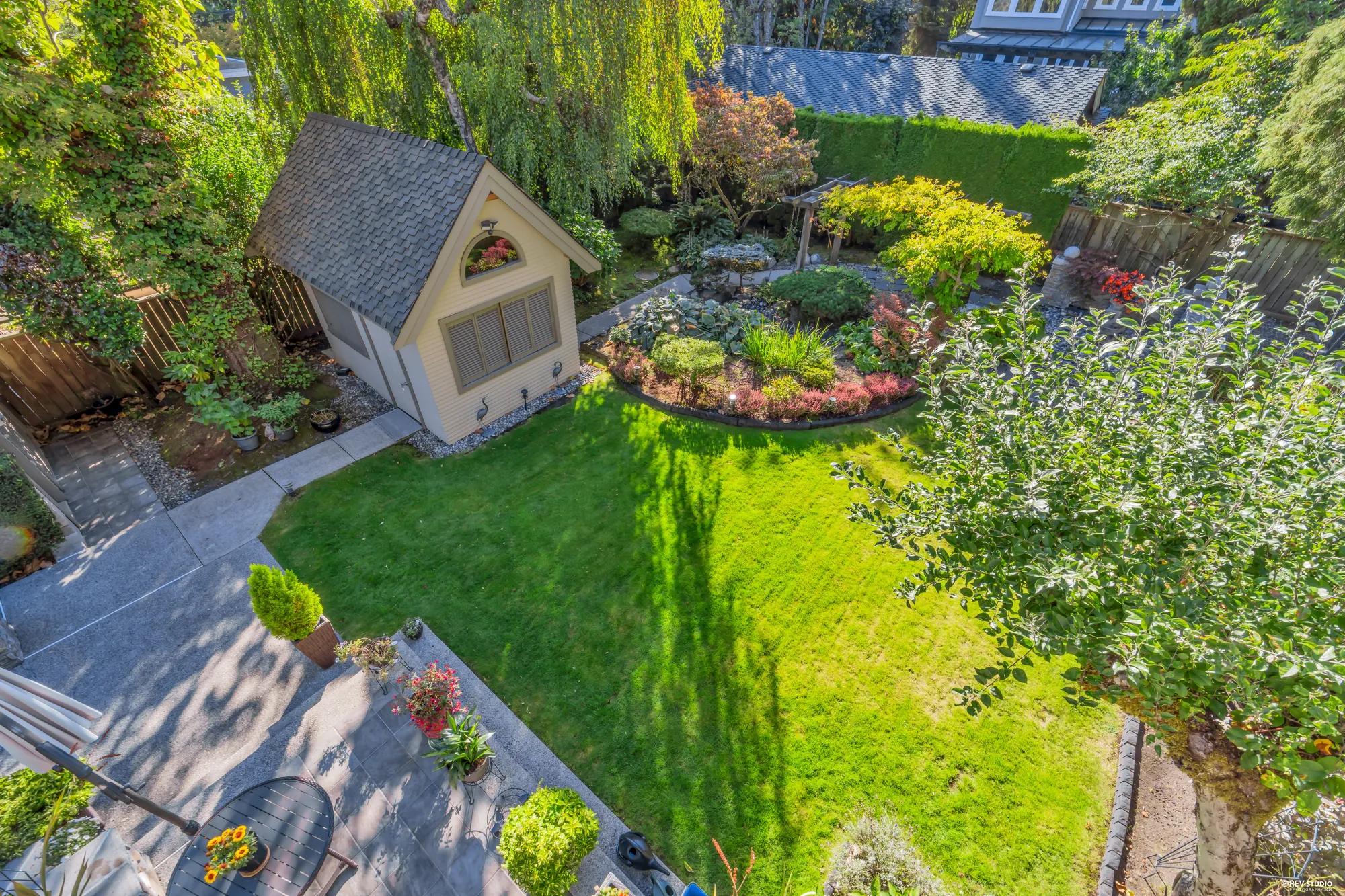 From the balcony, looking down the garden: the lawn, the pond garden, the pergola, the shed with its gable, hedges either side