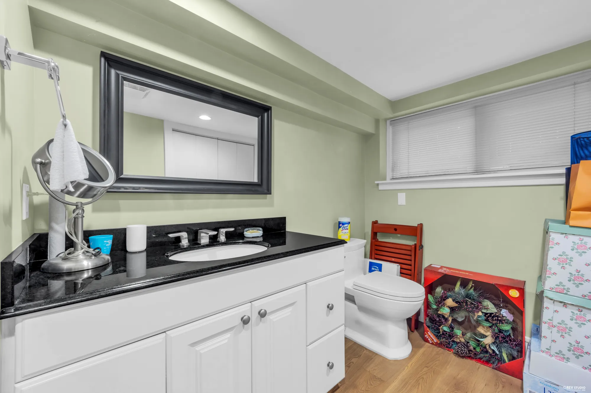 The lower bathroom: a white vanity with a black counter, green walls, a window