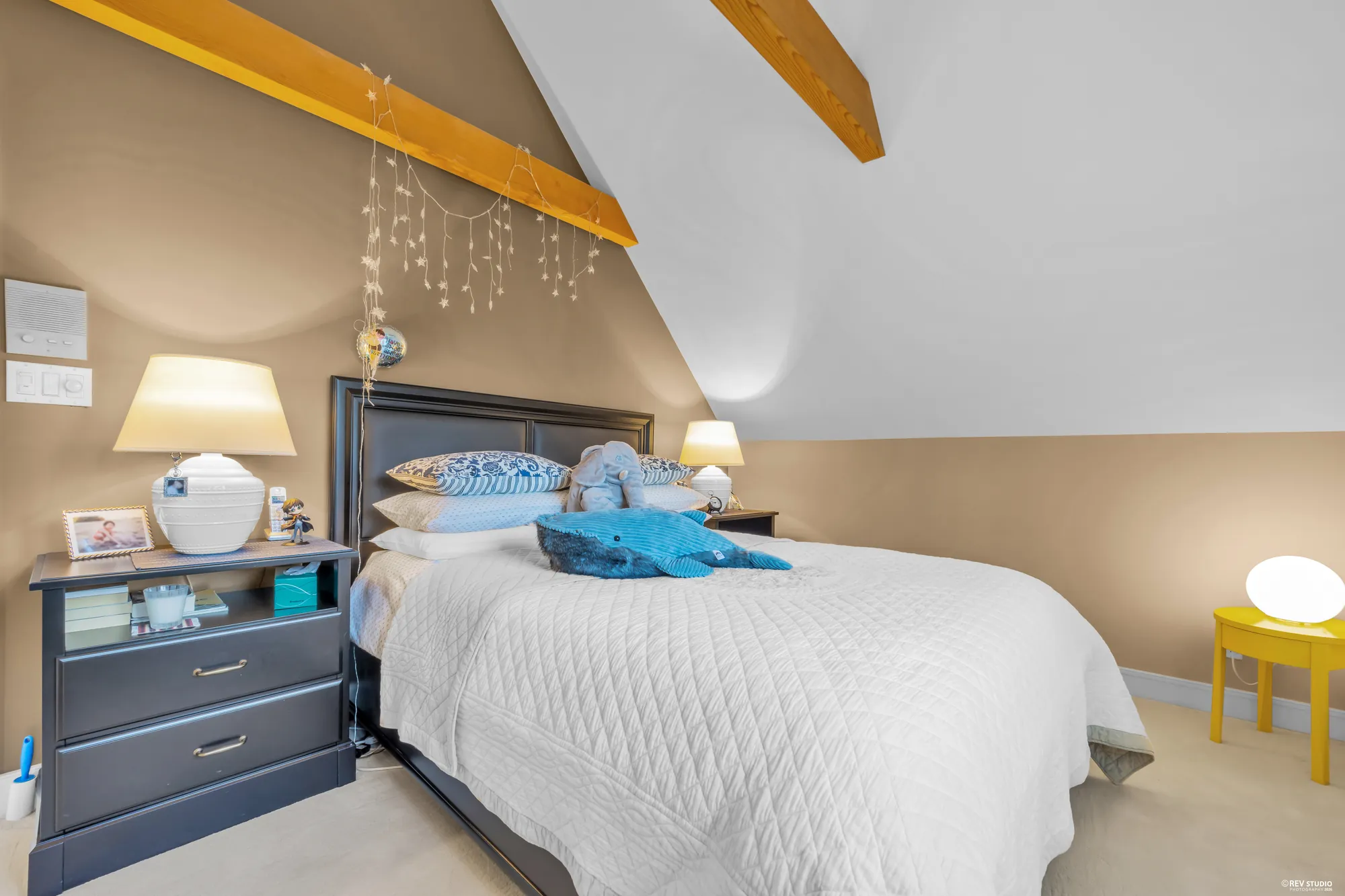 The same bedroom toward its bed and the beam above it