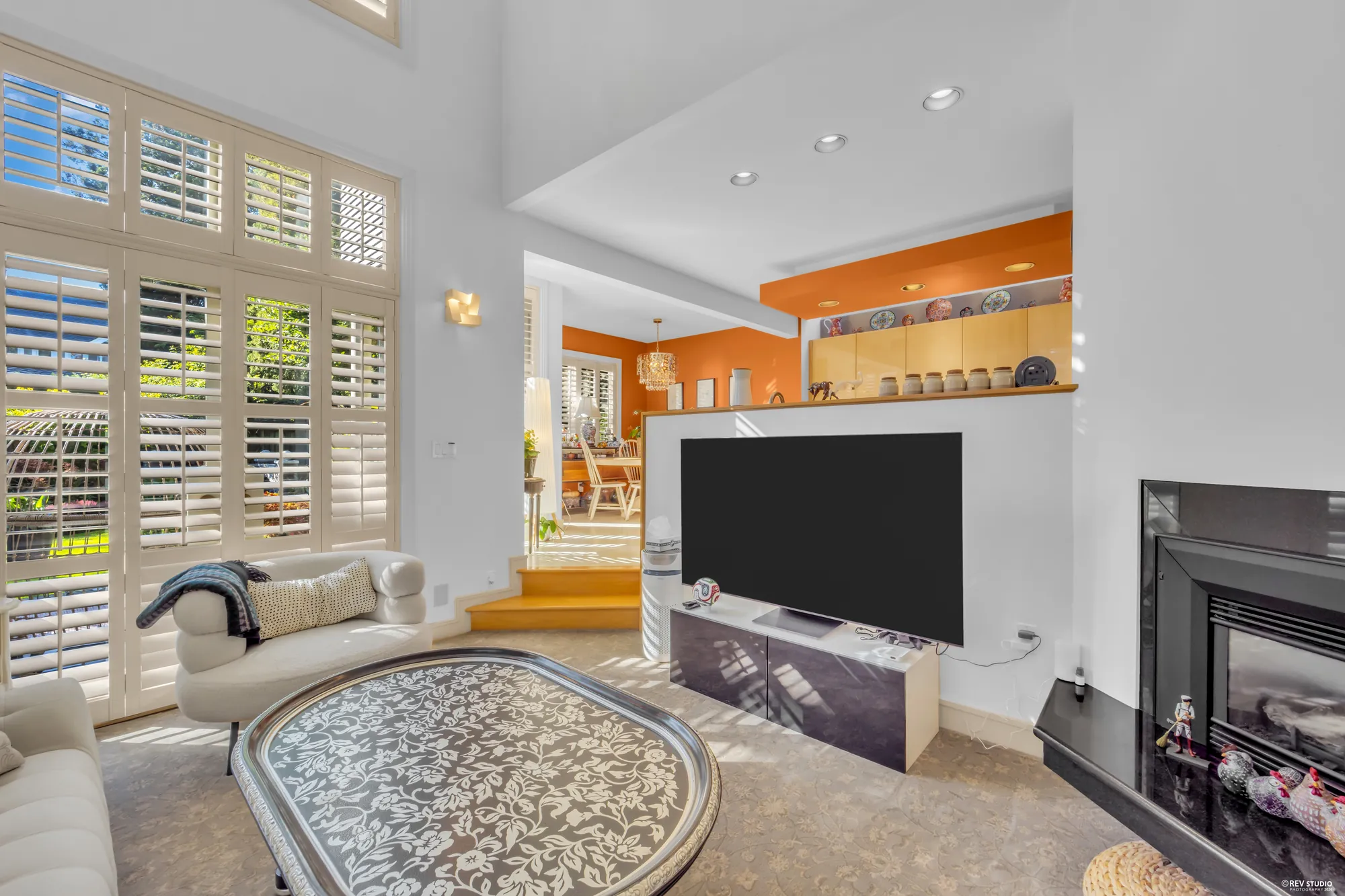 The family room's fireplace with the television beside it, the sofas, the shutters