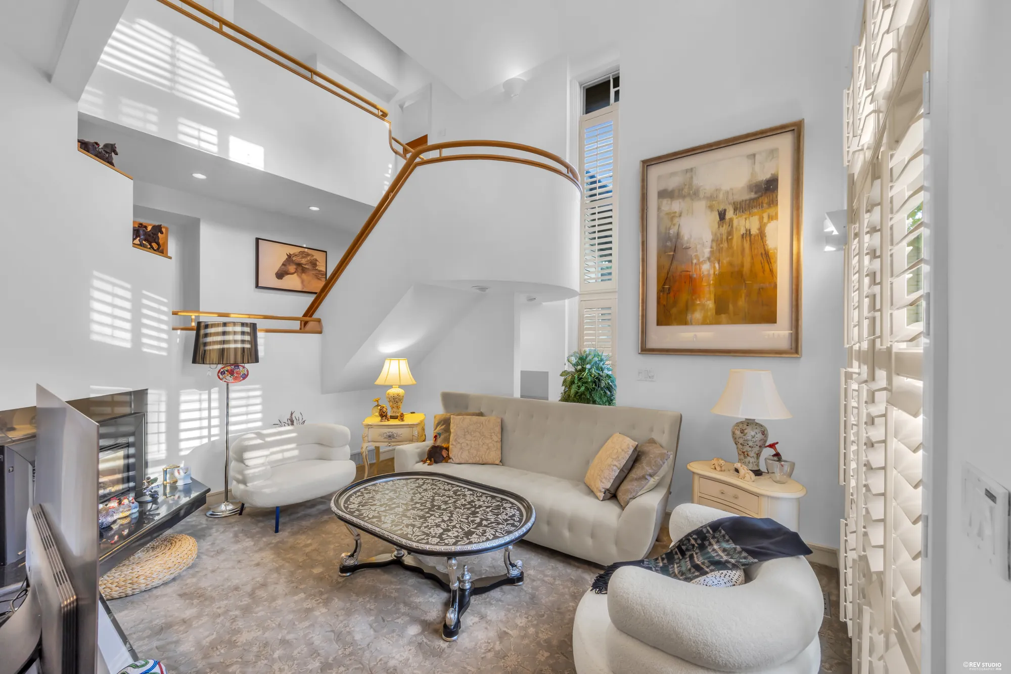 The family room's two-storey wall with the stair rail above and the shutters on the right