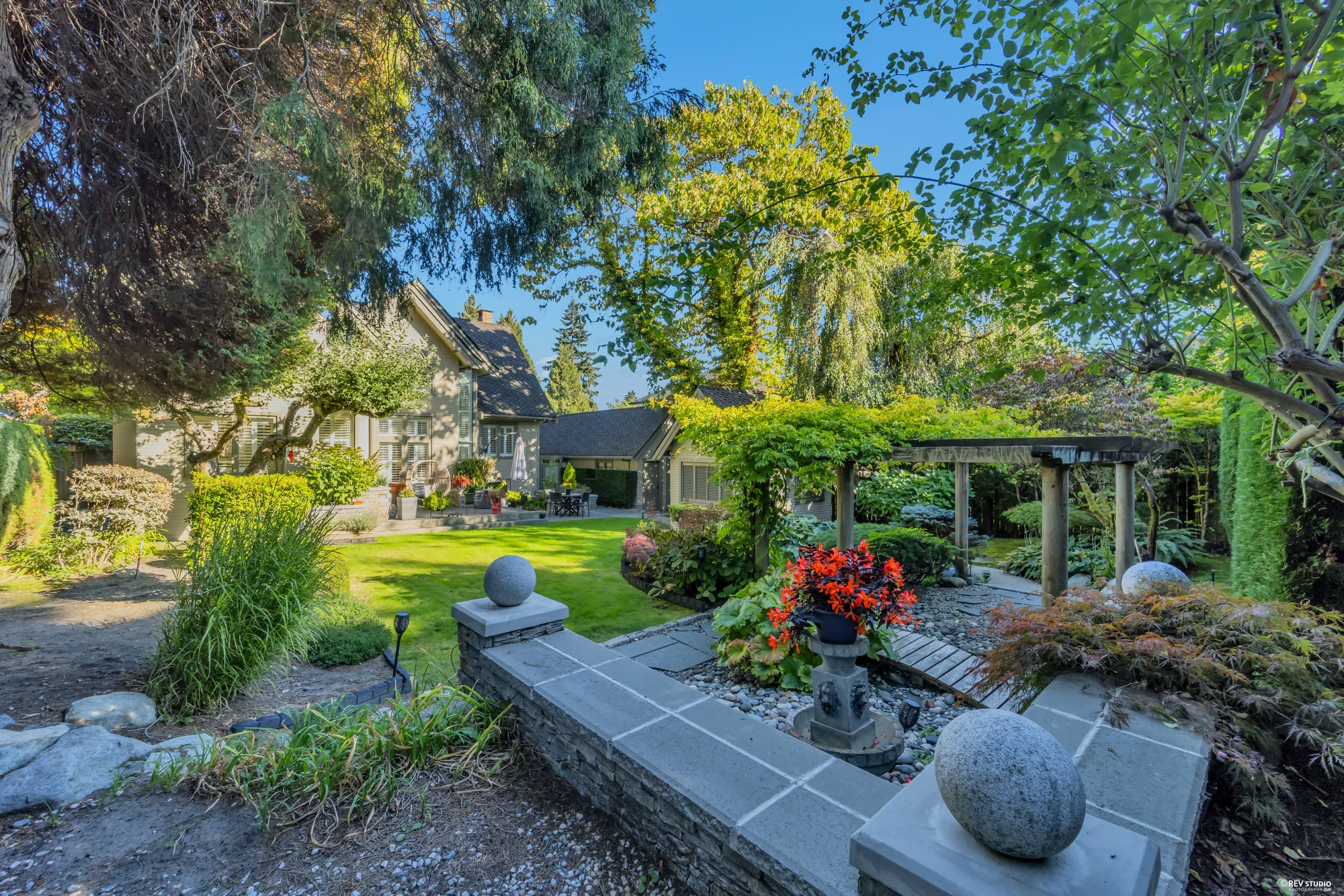 The pond garden: boulders, a stone path and a small bridge under trees and shrubs