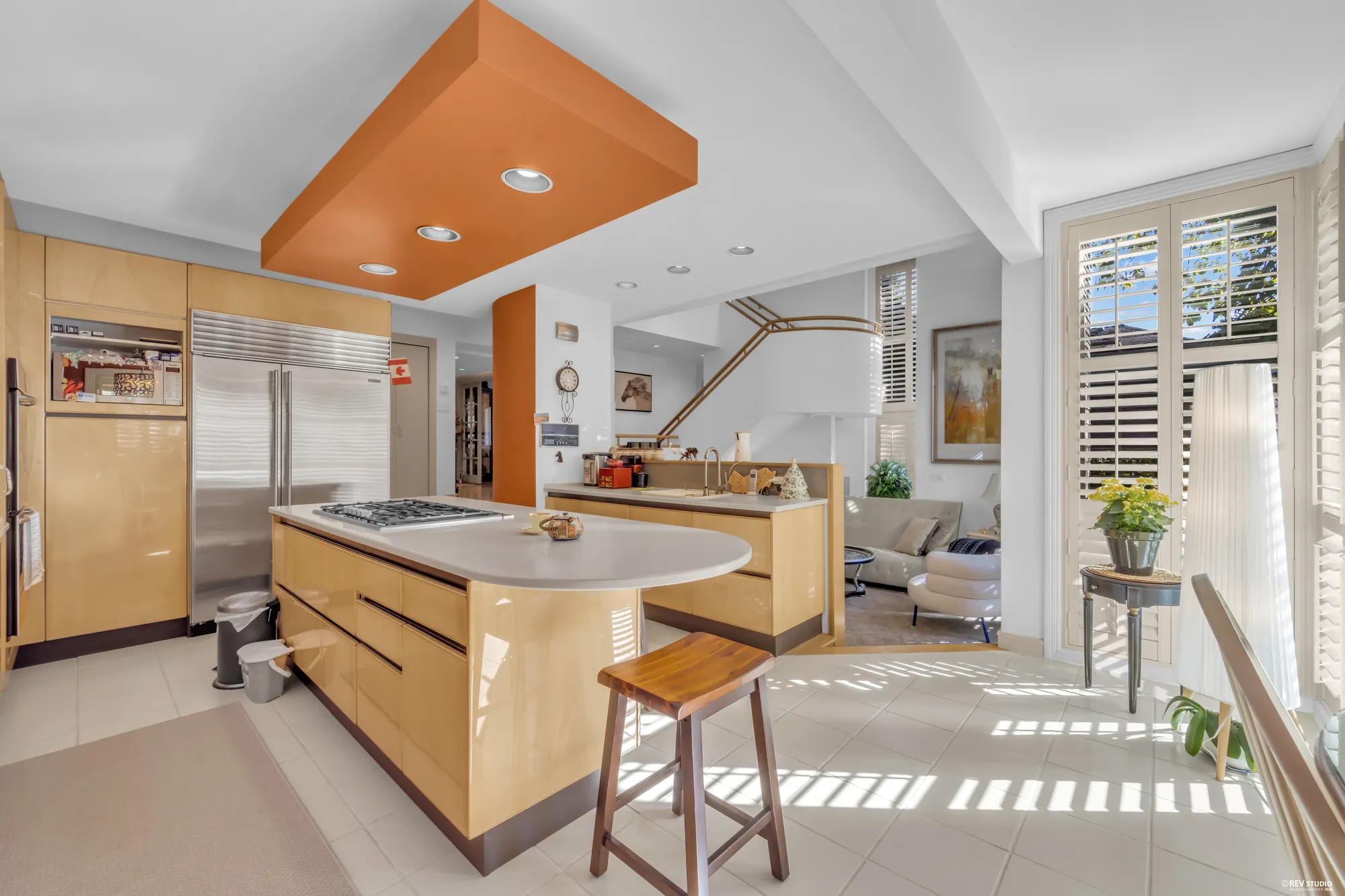 The kitchen toward the family room: the stainless refrigerator, the island's bar counter, the steps down on the right