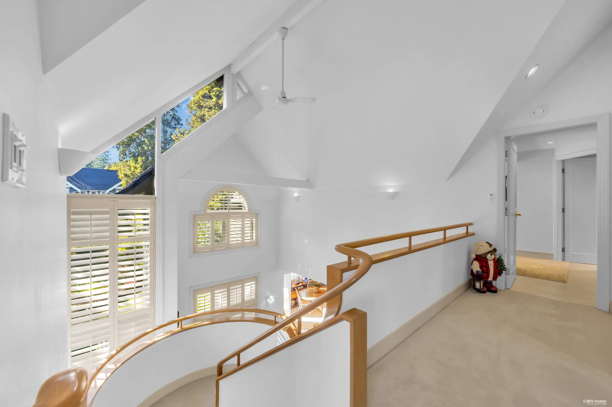 The landing: the curved oak rail over the family room, angled windows under the vault, the hall to the bedrooms on the right