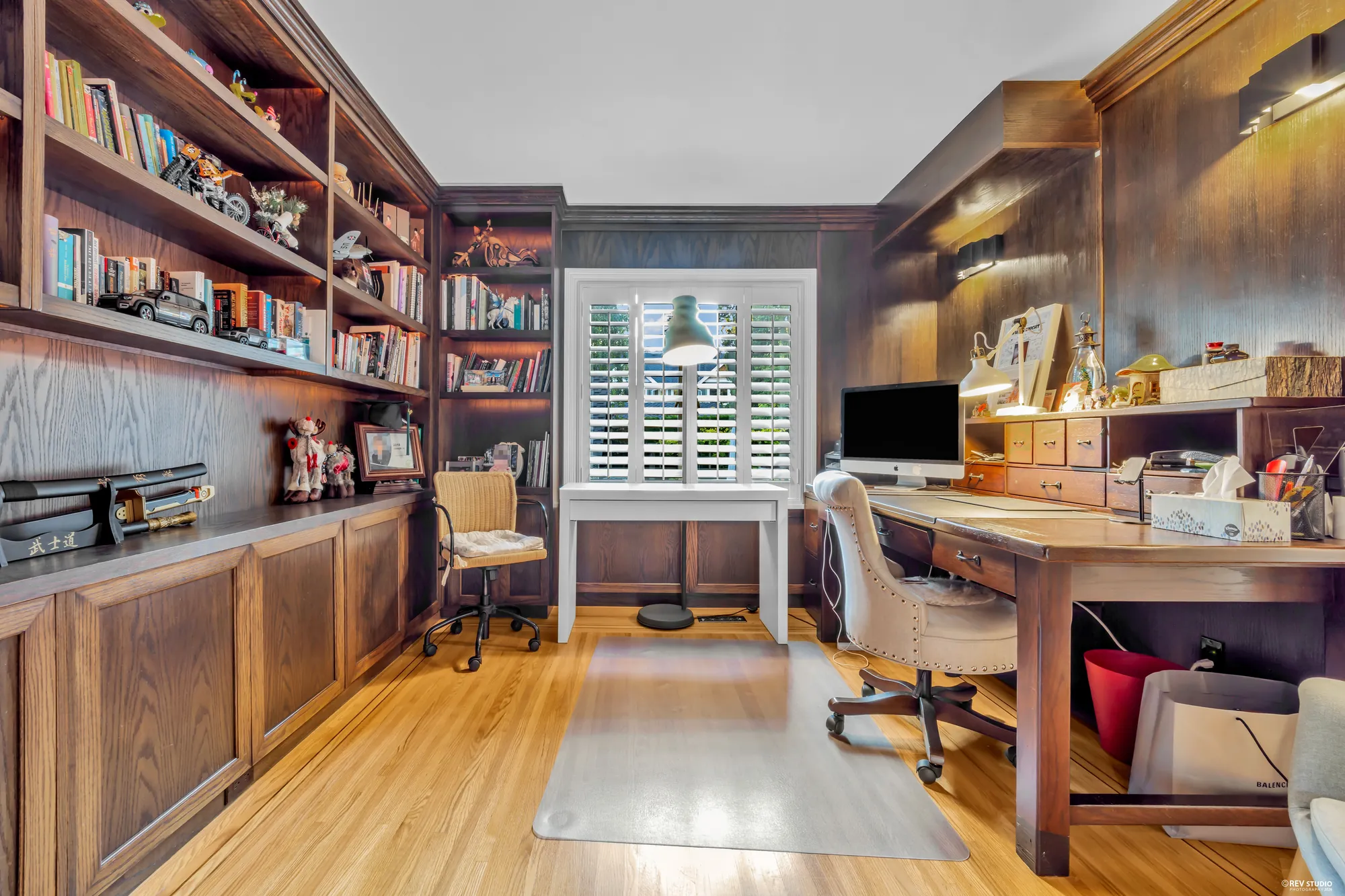The office: built-in shelves and a desk in dark wood, a shuttered window, hardwood