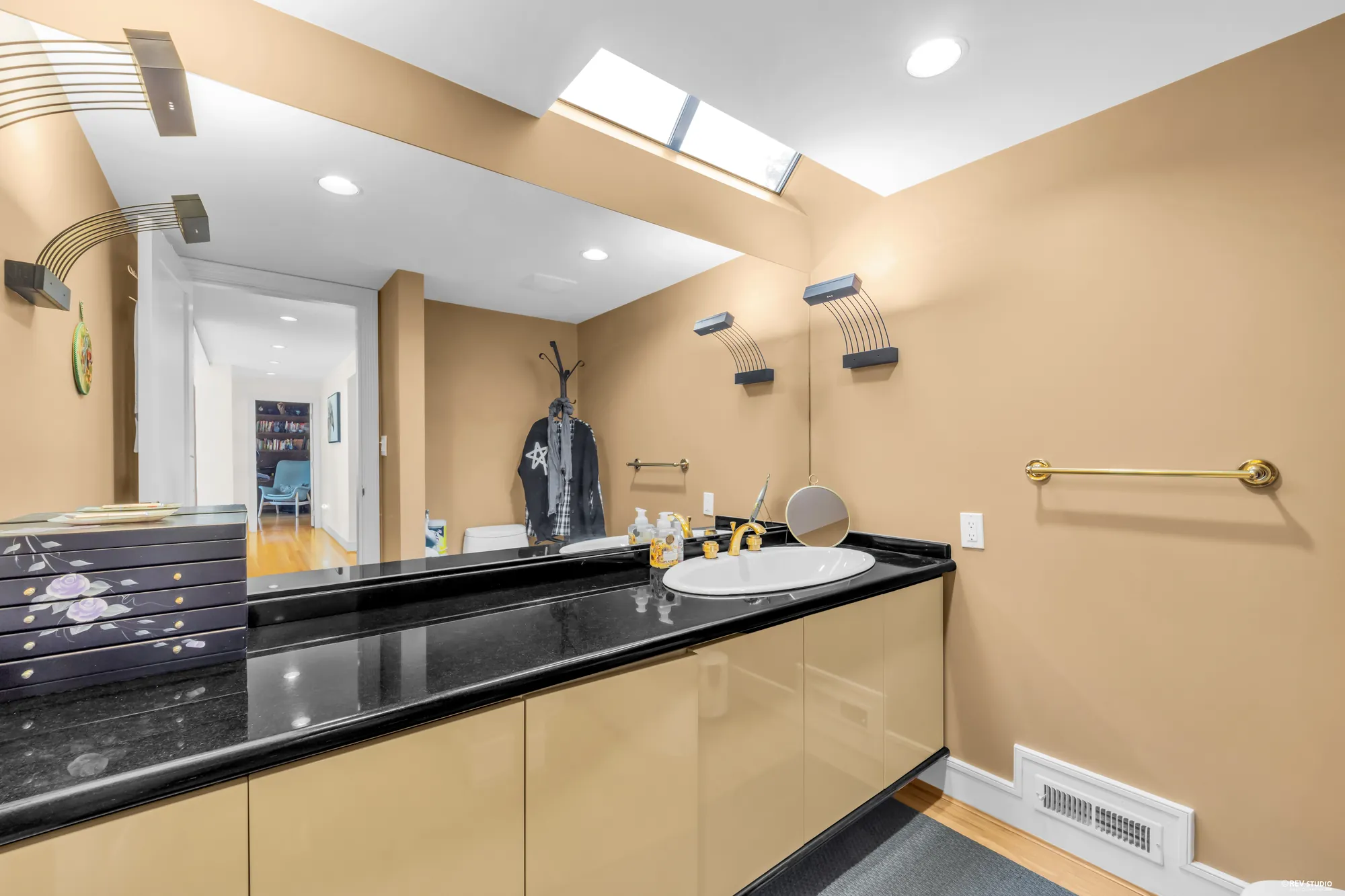 The two-piece bathroom: a black granite counter, a mirror wall, a skylight, the hall beyond the door