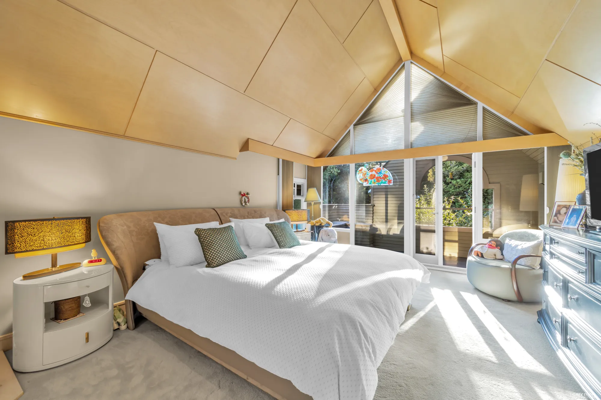 The primary bedroom toward the balcony, the wood ceiling, the dresser on the right