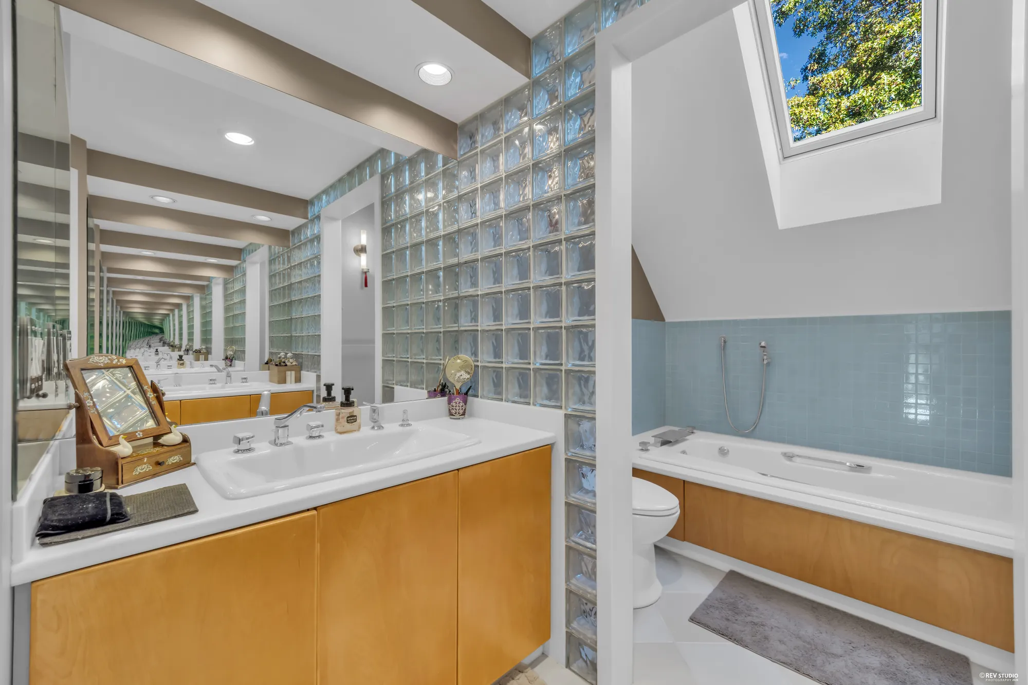 The primary bathroom's glass-block walls and the tub, the second vanity on the right